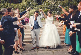 bride and groom walking through confetti line arms in the air